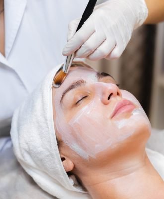 Esteticista aplicando mascarilla facial con brocha